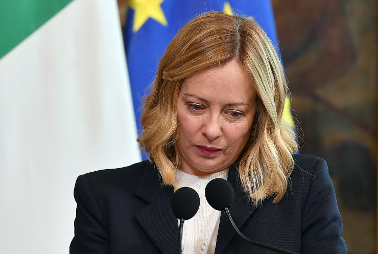 giorgia meloni davanti al microfono con dietro la bandiera dell'italia e dell'Unione europea