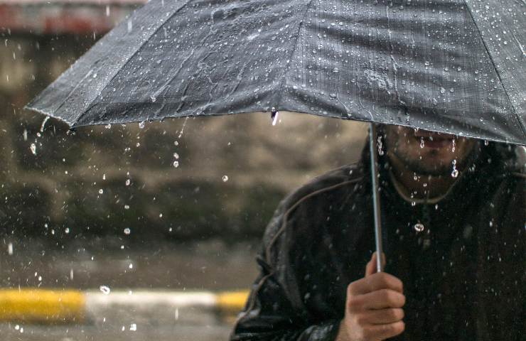 Uomo regge ombrello mentre piove