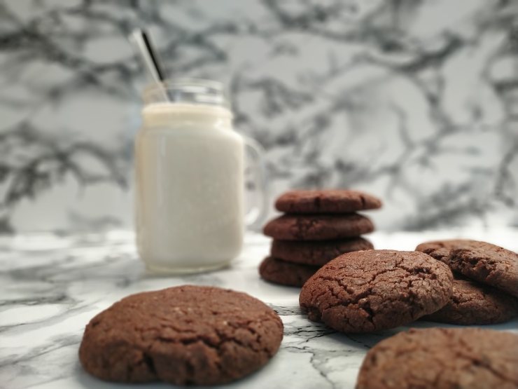 bicchiere con dentro del latte e una cannuccia circondato da biscotti al cioccolato