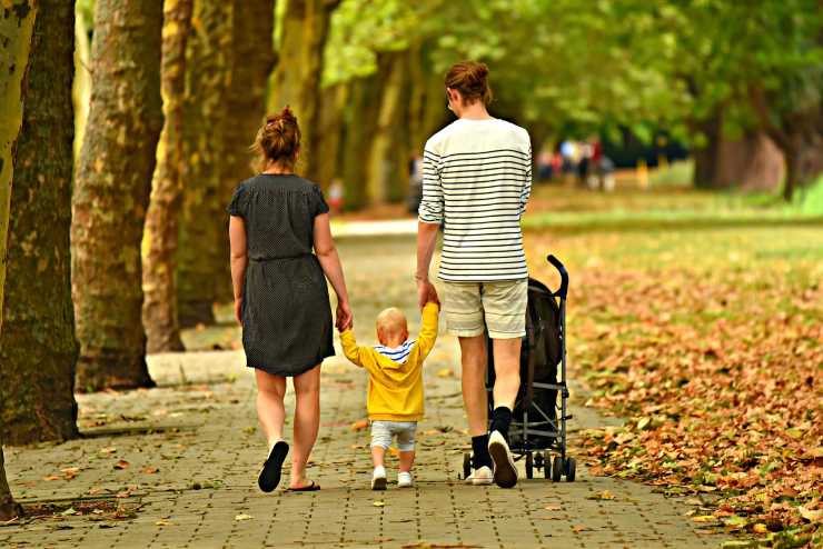 coppia che cammina e tiene per mano un bambino piccolo