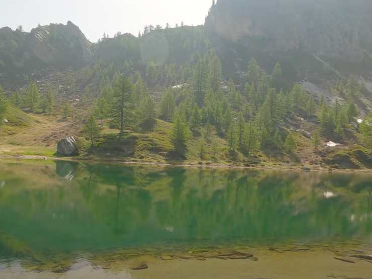 un lago e dietro monti e alberi