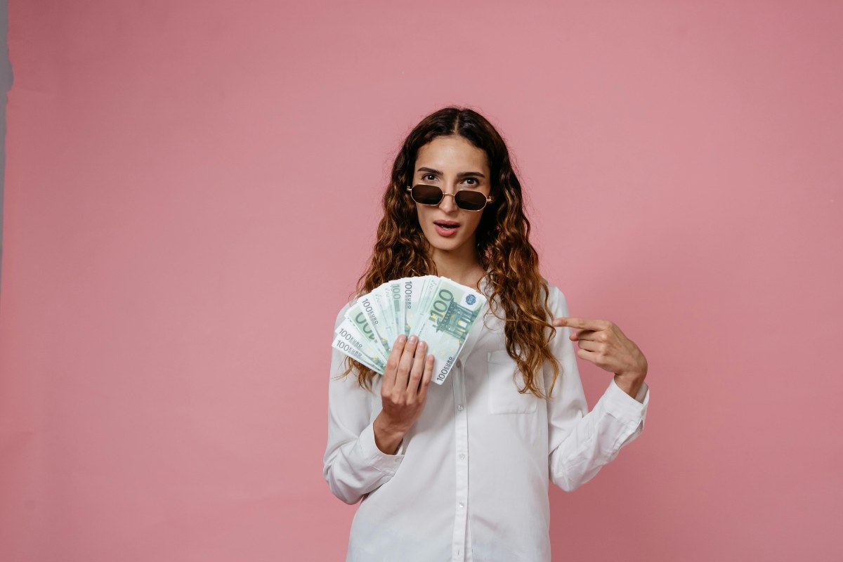 donna con in mano tante banconote da 100 euro e un espressione stupita