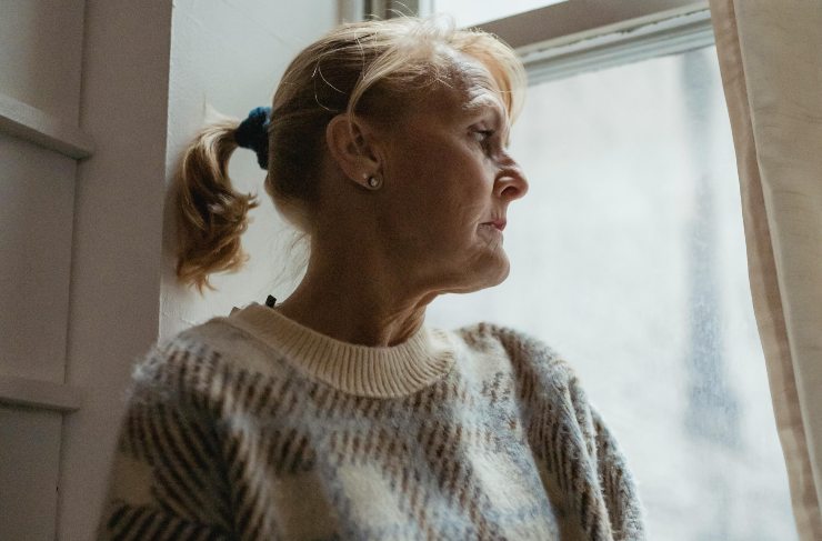 donna che guarda fuori dalla finestra con sguardo triste