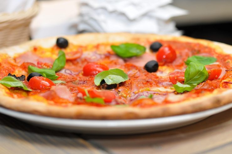 pizza con pomodoro olive nere e foglie di basilico