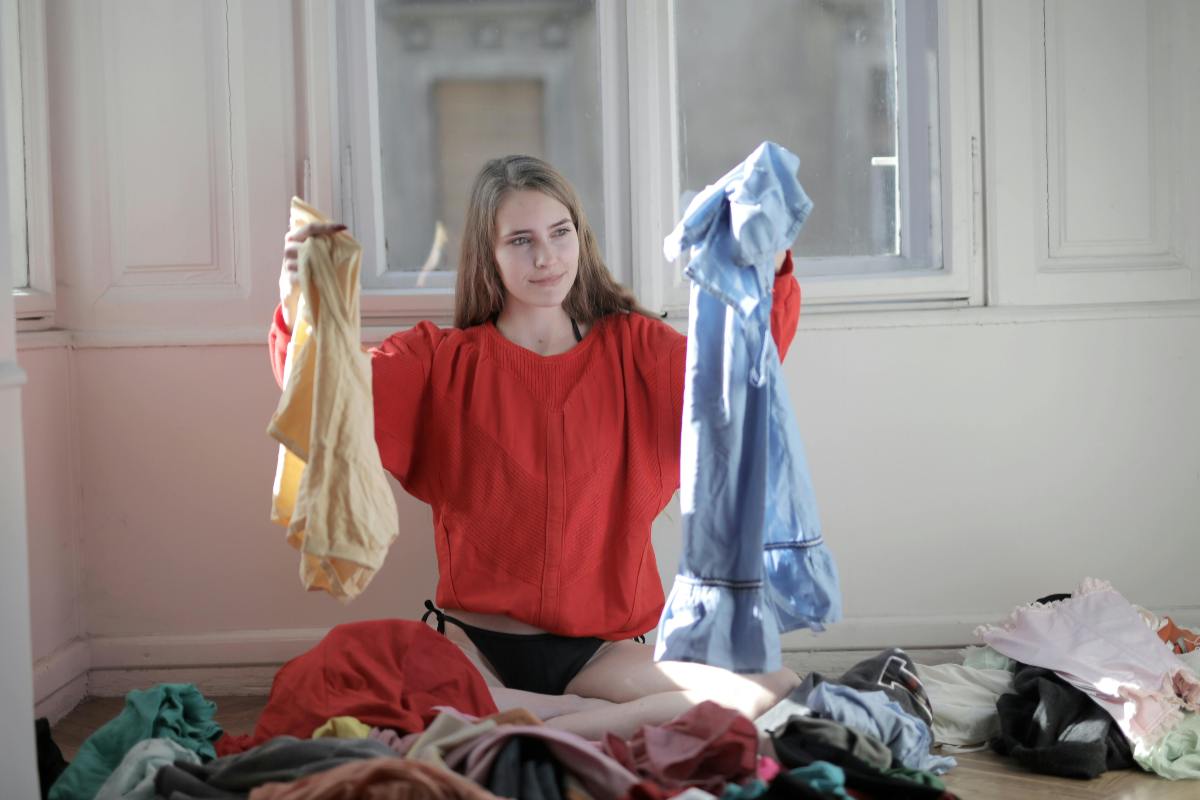 donna con in panno dei vestiti e altri abiti sul letto